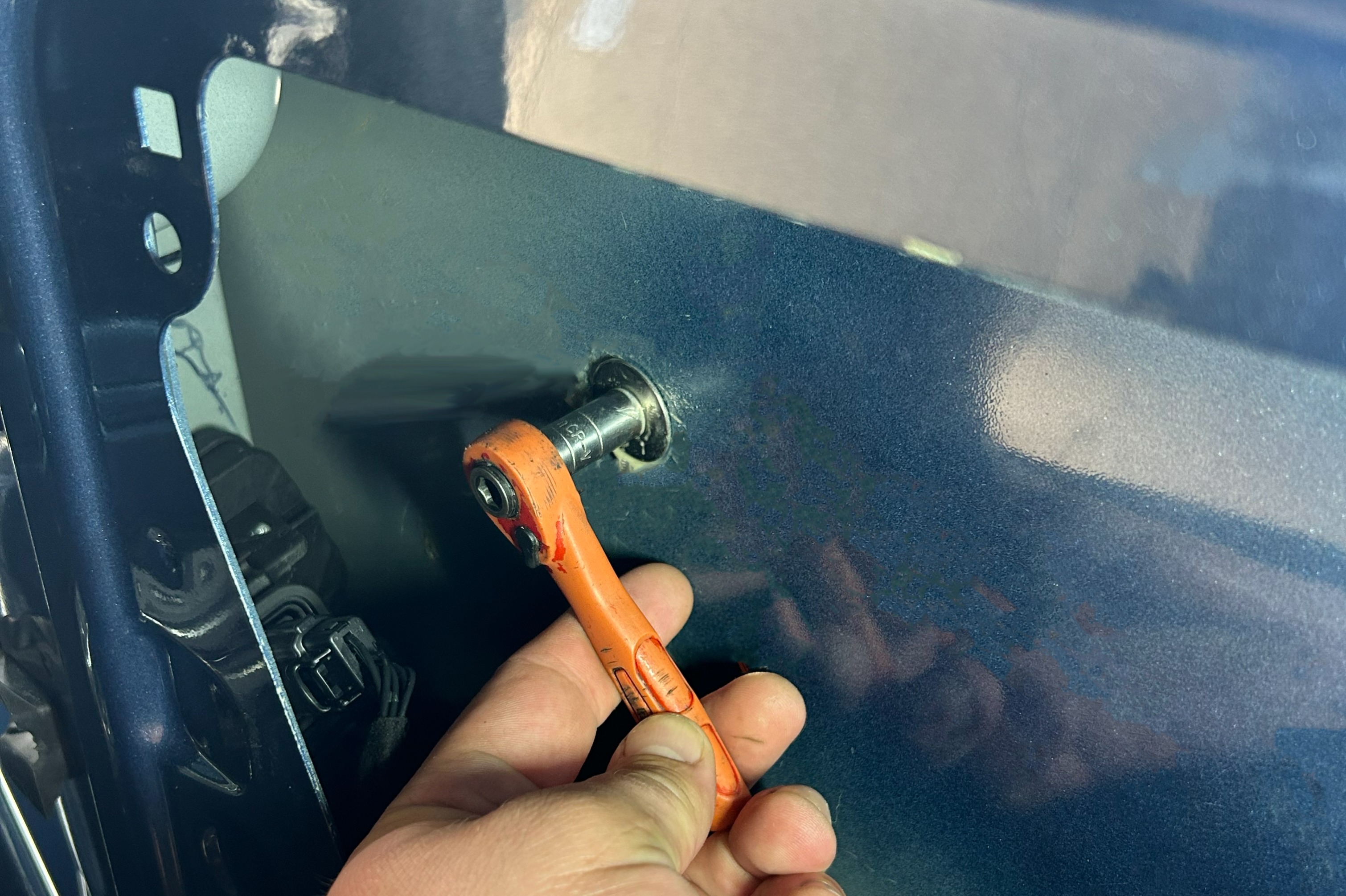 A ratchet tool tightening a nut of a shield from within a door